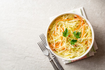 Fresh coleslaw salad in bowl on gray stone background.