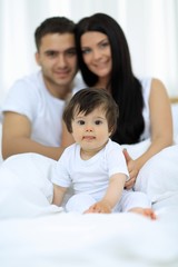 Fototapeta premium Happy couple and son sitting in bed