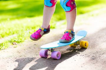 Child riding skateboard in summer park