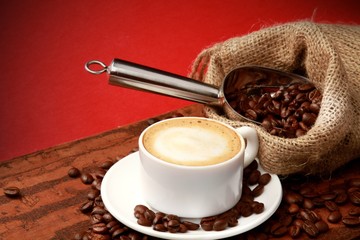 Cup of coffee surrounded by coffee beans