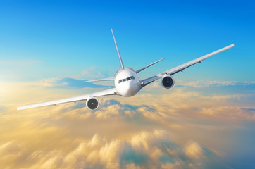 Fototapeta premium Samolot pasażerski leci z dużą prędkością na niebie ponad chmurami i pomarańczowym zachodem słońca, widok jest dokładnie na kokpicie pilotów.