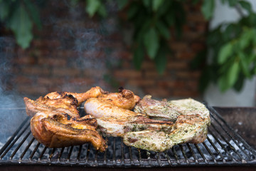 Steaks and chicken thighs on the grill, rest with friends in the open air