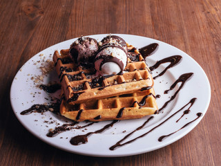 Fresh waffles with ice cream and maple syrup  on a wooden background