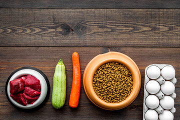 Dry food for dogs and cats based on raw meat and vegetables on dark wooden backgroud top view copy space