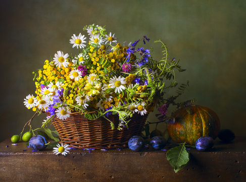 Still life with wild flowers in a basket and pumpkin