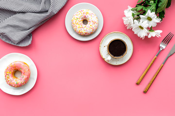 breakfast with coffee, donuts and flowers on pink background top view mockup