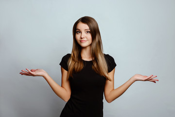 Positive emotions and feelings on white background.Caucasian female with long hair, wearing black T-shirt,  shrugs shoulders as doesnt know answer, being clueless and uncertain. 