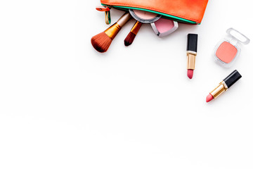 Decorative cosmetics background. Eyeshadow, rouge, brushes, lipstick in cosmetic bag on white top view copy space