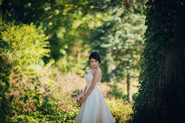 Beautiful blonde bride poses with orange wedding bouquet in the 