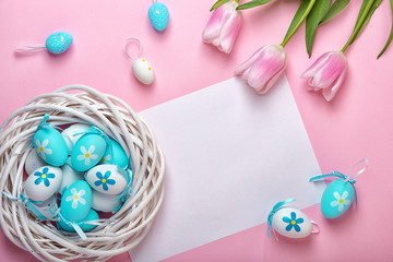 Easter eggs in a wicker basket and a bouquet of tulips on a pink background. Holiday greeting card for Easter!