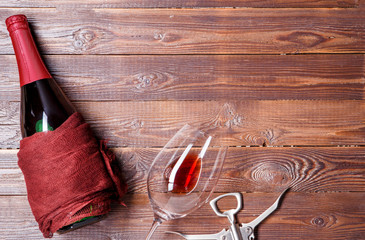 Photo of bottle of wine, corkscrew, wine glass on brown
