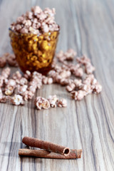 chocolate flavored popcorn in the yellow glass and on the brown wood table with cinnamon background