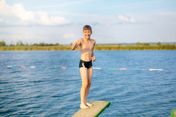 sporty cute young boy jumps very high from pier and having fun on his vacation by the sea © Natali