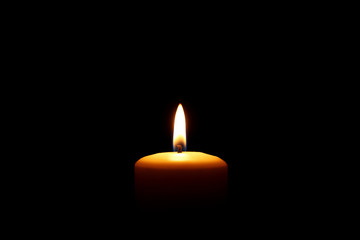 Burning candle on black background