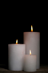 White burning candles on black background