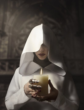 Sorceress In White Hooded Cloak Holding A Burning Candle Standing In The Castle.