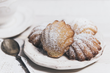 Homemade french madeleines with beurre noisette on white wooden table