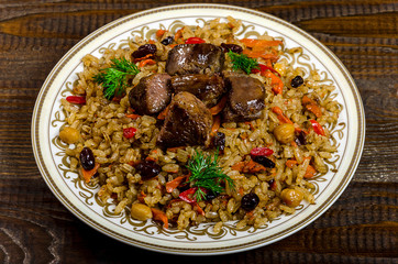 Uzbek national pilaf dish on a dark wooden background