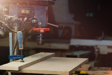Close-up of Vertical Drilling Machine with wooden plank pattern in Workshop with Copyspace.