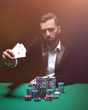 Happy poker player winning and holding a pair of aces Photos | Adobe Stock