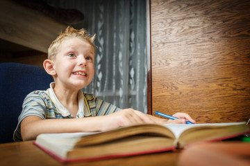 Happy boy with smile face and looking at camera doing homework