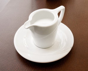 coffee creamer on a saucer on a table in a restaurant. Mini pitcher full of milk,