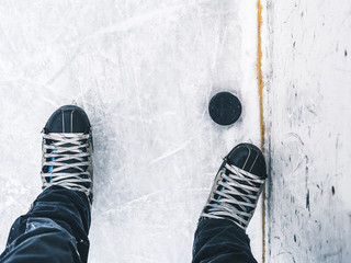 top down view of hockey puck and skates on ice