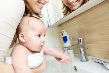 Mother wahing baby hand . Child get accustom for  cleanness. Mom and son having fun together in bathroom. Hygiene and healthcare for children