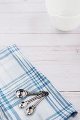 Measuring spoons sit on top of a plaid dishtowel