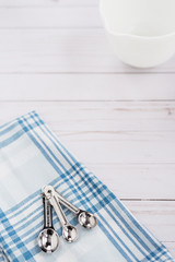 Measuring spoons sit on top of a plaid dishtowel
