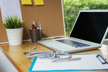 Stethoscope with clipboard and Laptop on desk,Doctor working in hospital writing a prescription.