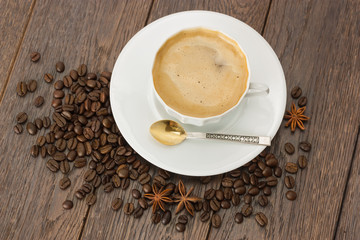 A Cup of coffee and coffee beans on wooden table.