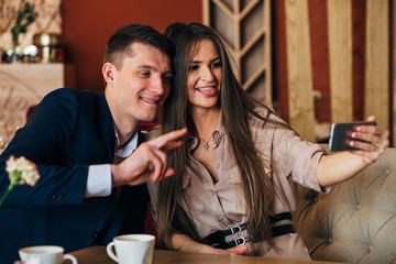 Happy young couple taking selfie with smart phone at cafe