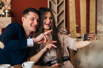Happy young couple taking selfie with smart phone at cafe