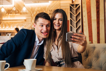 Happy young couple taking selfie with smart phone at cafe