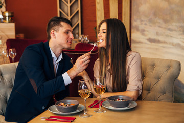 a man feeds his woman in a restaurant
