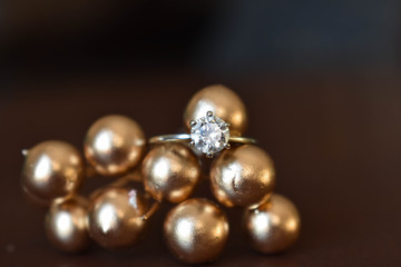 Close up diamond engagement ring resting on golden balls