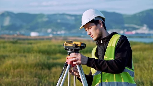 Surveyor engineer is measuring level on construction site. Geodesist ensure precise measurements before undertaking large construction projects. Concept of landscape design