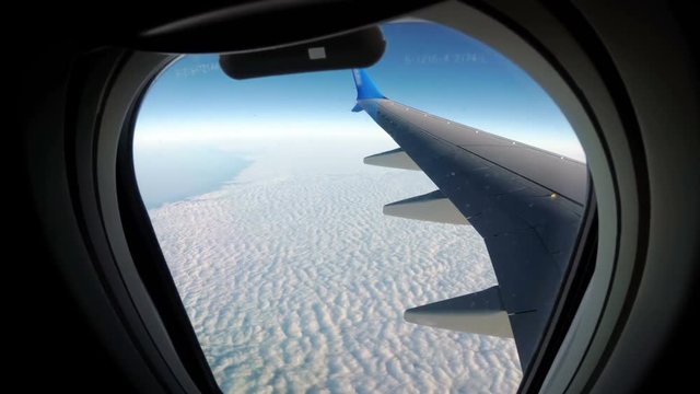Clouds are Seen through the Window of a Jet Airplane. View from the Airplane Window on a Landscape of Clouds. Airplane flies above the weather