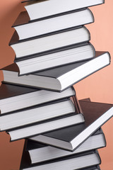 A stack of books on a pink background, side view