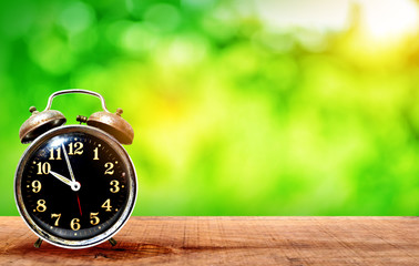 Retro clock on wooden with Nature green bokeh background on a light green - dark green