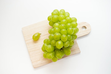 Green grapes on chopping board isolated on white background