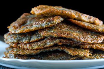a stack of potato pancakes on a white plate on a wooden background. Home kitchen.