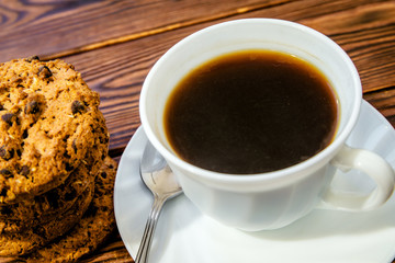 A cup of hot coffee stands on a wooden table 