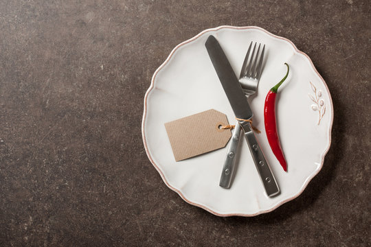 Table setting with cutlery, chili pepper and paper tag