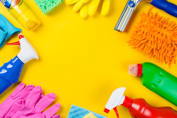 Cleaning concept - cleaning supplies on wood background