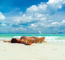 Fototapeta na wymiar Cute woman relaxing on the summer tropical beach. White sand, blue sky and crystal sea of tropical beach. Vacation in Paradise. Ocean beach relax, travel to islands