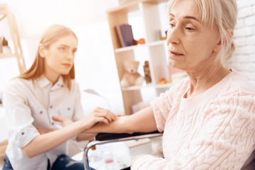 Fototapeta premium Girl is nursing elderly woman at home. Girl is using drop counter to help woman.