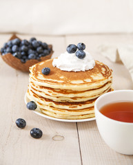 Pancakes with tea for breakfast / Pancakes with whipped cream and berries on a white wooden table