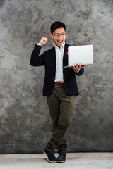 Full length portrait of an excited young asian man